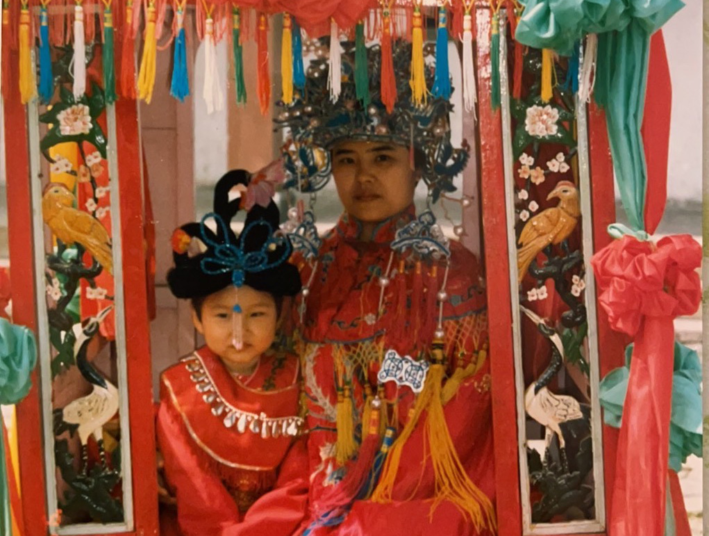 Yang as a child with her mother posing for photos in traditional attire. Red is considered a lucky colour in Chinese culture.